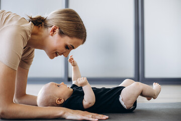 Mother with toddler daughter exercising on mat