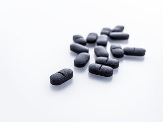 black oval pills on a white table. dietary supplements, drugs concept