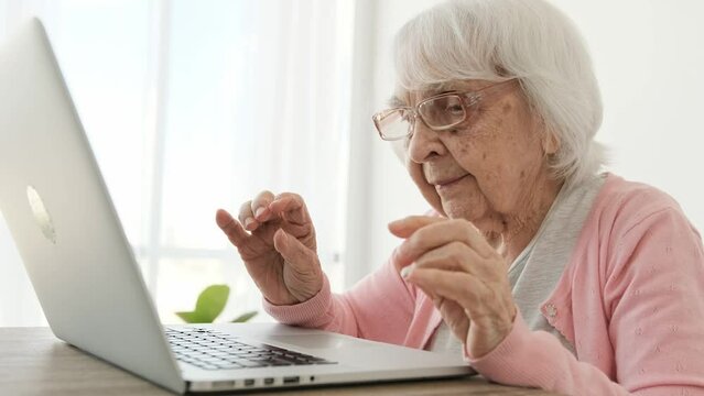 Senior woman wearing glasses to work with laptop. Elderly female person discovering modern technologies