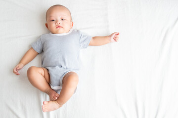 The top view image has a side area , is a baby boy wearing a striped shirt. Lie with your legs up and your arms outstretched on the bed.