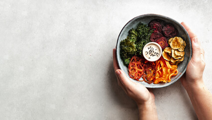 Hands holding a bowl of vegetable chips, healthy food concept, banner, top view