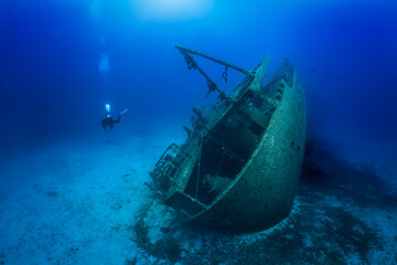 A scuba diver explores a sunken shipwreck at the bottom of the mediterranean sea, Greece