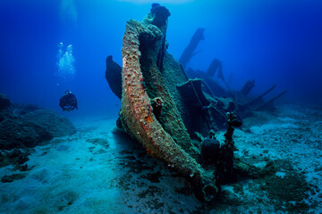 A scuba diver explores a sunken shipwreck at the bottom of the mediterranean sea, Greece