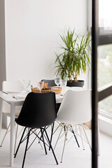 Modern interior of cozy kitchen, dining room, white furniture, chairs, bowls. Conceptual decor design, advertising, home loan mortgage for a young family, magazine cover. Soft selective focus.