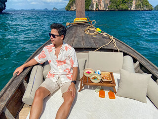 man tourist in private longtail boat trip to island with exotic food picnic, Krabi, Thailand....