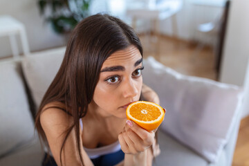 Sick woman trying to sense smell of half fresh orange, has symptoms of Covid-19, corona virus...