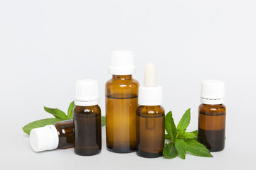 Natural Mint Essential Oil in a Glass Bottle. organic cosmetics with herbal extracts of mint on colored background