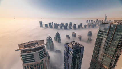 Rare early morning winter fog above the Dubai Marina skyline and skyscrapers rooftops aerial...
