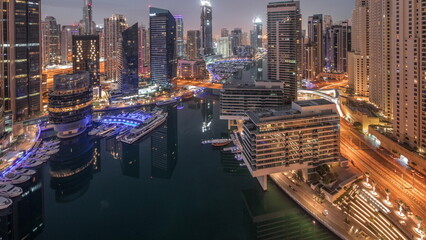 Aerial view to Dubai marina skyscrapers around canal with floating boats night to day timelapse