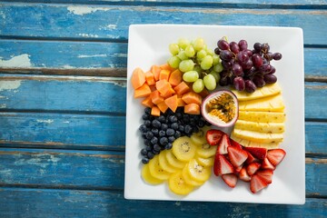Fresh fruits in white plate on blue table