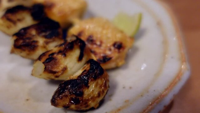 Japanese street izakaya food, yakitori chicken skin and garlic skewer barbecue side with salt and lime