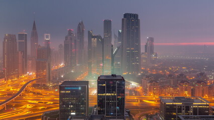 Fototapeta Panorama of Dubai Financial Center district with tall skyscrapers with illumination night to day timelapse. obraz