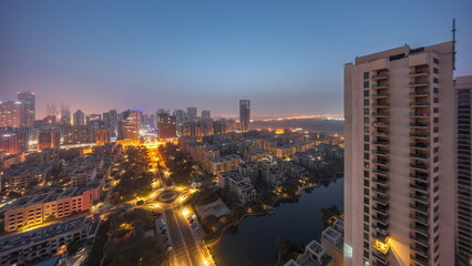 Obraz premium Skyscrapers in Barsha Heights district and low rise buildings in Greens district aerial night to day timelapse.