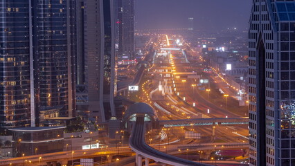 Busy Sheikh Zayed Road aerial night to day timelapse, metro railway and modern skyscrapers around in luxury Dubai city.