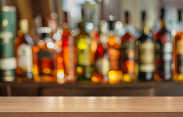 Wooden table top and beautiful bokeh shelves with alcohol bottles at the pub background. Bar...