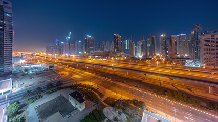Dubai Marina skyscrapers and Sheikh Zayed road with metro railway aerial night to day timelapse, United Arab Emirates