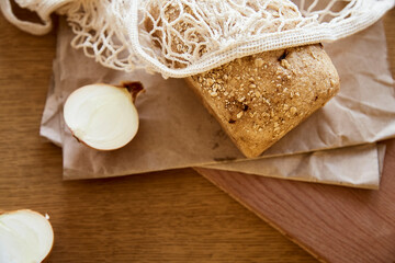 Organic sourdough unleavened onion bread with oatmeal on craft paper. Loaf of natural freshly baked bread. Beige rustic food background.