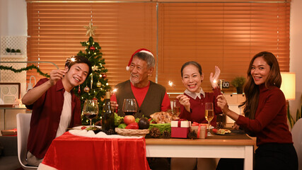 Happy family are having dinner at home, celebrating Christmas or New Year party with sparklers
