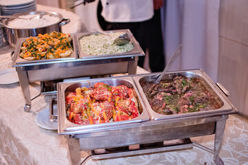 a table with a buffet to serve on top, with rice, meat and potatoes