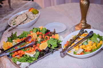 a table with three plates of assorted salads
