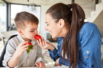 Mother feeds her little son with a strawberry