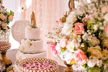 trays with sweets, brigadeiros in pink molds, flowers and a cake in the background