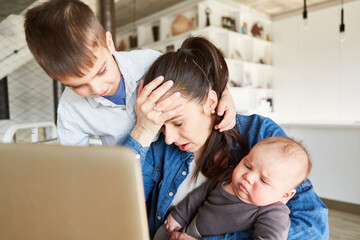 Stressed mother multitasking in home office
