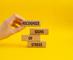 Recognize Signs of Stress symbol. Concept words Recognize Signs of Stress on wooden blocks. Beautiful yellow background. Businessman hand. Medicine and Business concept. Copy space