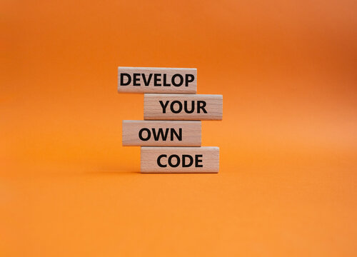 Develop your own code symbol. Concept words Develop your own code on wooden blocks. Beautiful orange background. Business and Develop your own code concept. Copy space.
