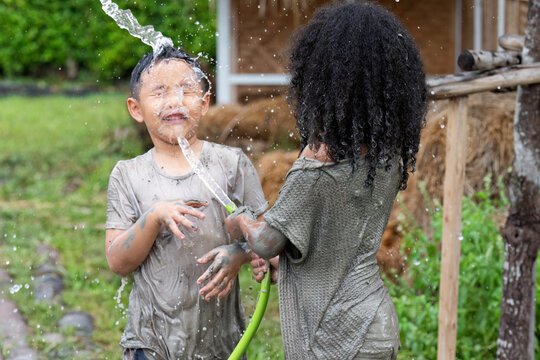 Kid dirty play from muddy water they come cleaning by spray tap water hose to face and body
