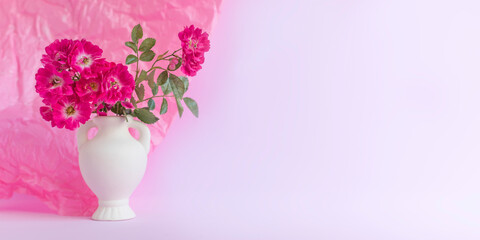 Pink roses in a white vase. Festive Pastel pink background.Floral card, selective focus, toned, copy space.Banner