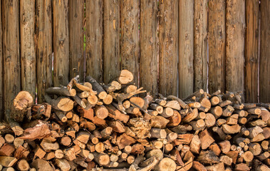 Firewood is split and stacked for the winter heating season. Background of stacked firewood, chopped wood for the stove.