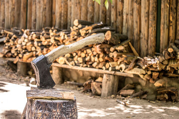 Firewood is split and stacked for the winter heating season. Background of stacked firewood, chopped wood for the stove. Ax for cutting wood.
