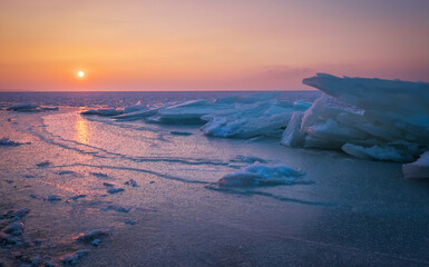 Sunrise and frozen sea. Beautiful winter landscape with lake and red sun in morning time. Daybreak