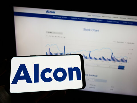 Stuttgart, Germany - 08-28-2022: Person holding mobile phone with logo of eye care company Alcon AG on screen in front of business web page. Focus on phone display.