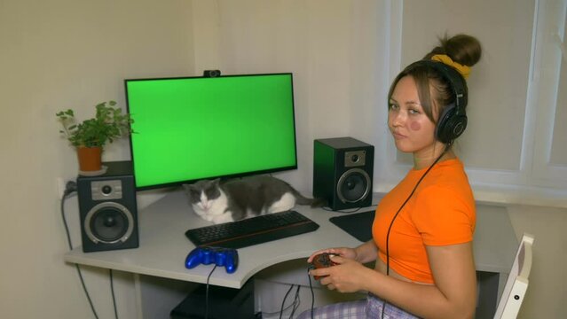 Gamer girl loses the computer game and shakes her head. Playing a computer game with joystick. Video with a chroma key on the screen to insert any video or image.