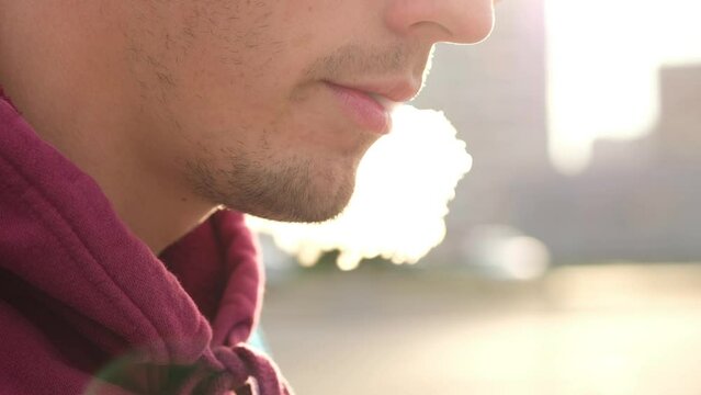 Young man smoke vape pod system outdoors. Male inhales and exhales vapor of electronic cigarette.