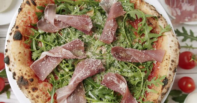 Prosciutto pizza with strachatella cheese, tomatoes, arugula leaves. Delicious Pizza with prosciutto parma ham, arugula salad rocket on white background with ingredients. Top view. Italian cuisine. 