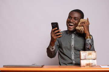 excited african man using a bundle of money like a phone
