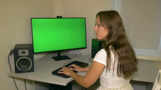 Girl is typing text on the keyboard then guy hits her with slipper. Chromakey on computer screen. She turns around with a rude face. Video with a chroma key on the screen to insert any video or image