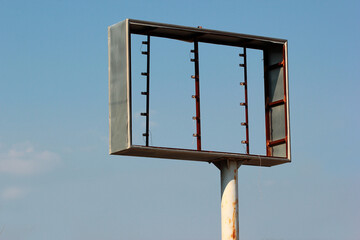 Old frame of an abandoned free-standing billboard against blue sky background