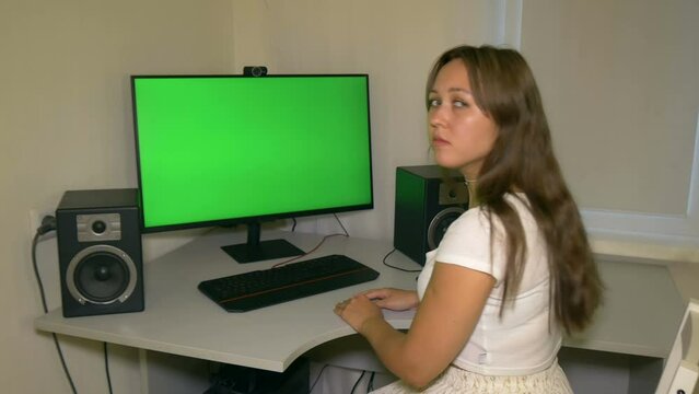 Girl is very sad with what is shown on the computer screen. Chromakey on computer screen. Video with a chroma key on the screen to insert any video or image.