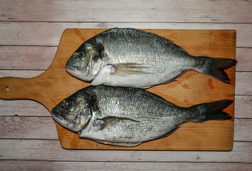 Fish consumption - concept. Fish ready to be cooked. Two fish on the wood chipper. Sea bream. 