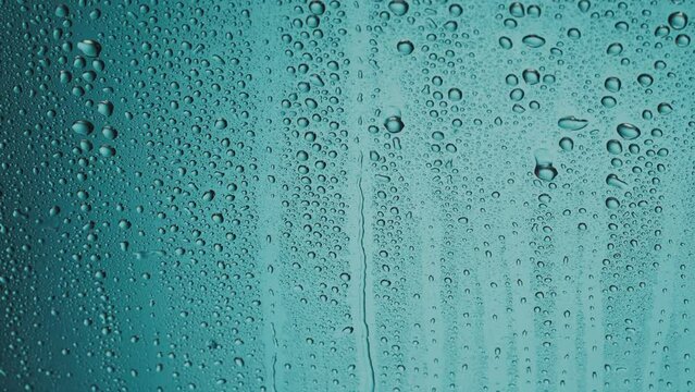 Water droplets run down the blue glass