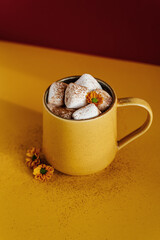 Still life of a yellow mug of hot cocoa with marshmallows.