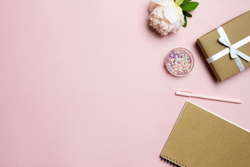Brown notebook with pink roses, gift box and pen on pink background. 