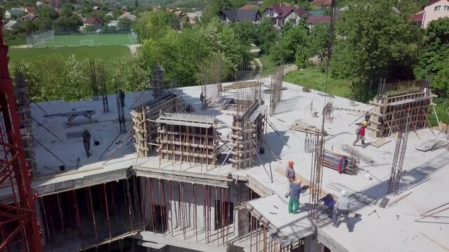 image from above during the summer of a block of flats, you can see the workers who have a helmet and shape and a tower crane