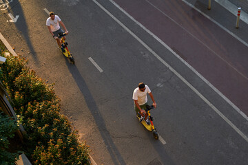 Mans are riding on kick scooter on cycling road. Top aerial view.