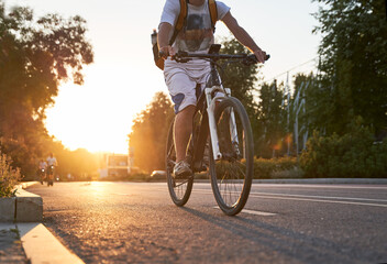 Naklejka na ściany i meble Man is riding on bicycle on the street on the sunset.