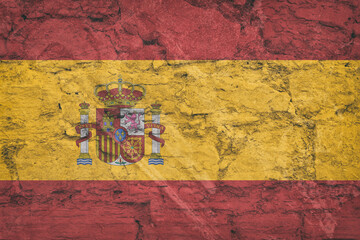 The national flag of Spain on stone wall, grunge background. Spanish flag depicted in bright paint colors on old relief plastering wall